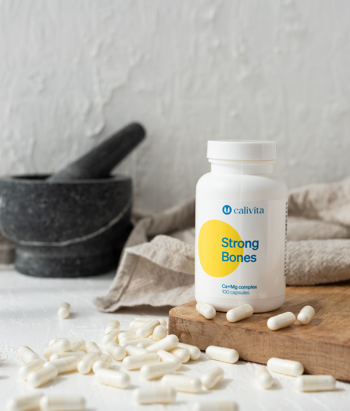 flacon strong bones si capsule albe cu calciu si magneziu pe masa