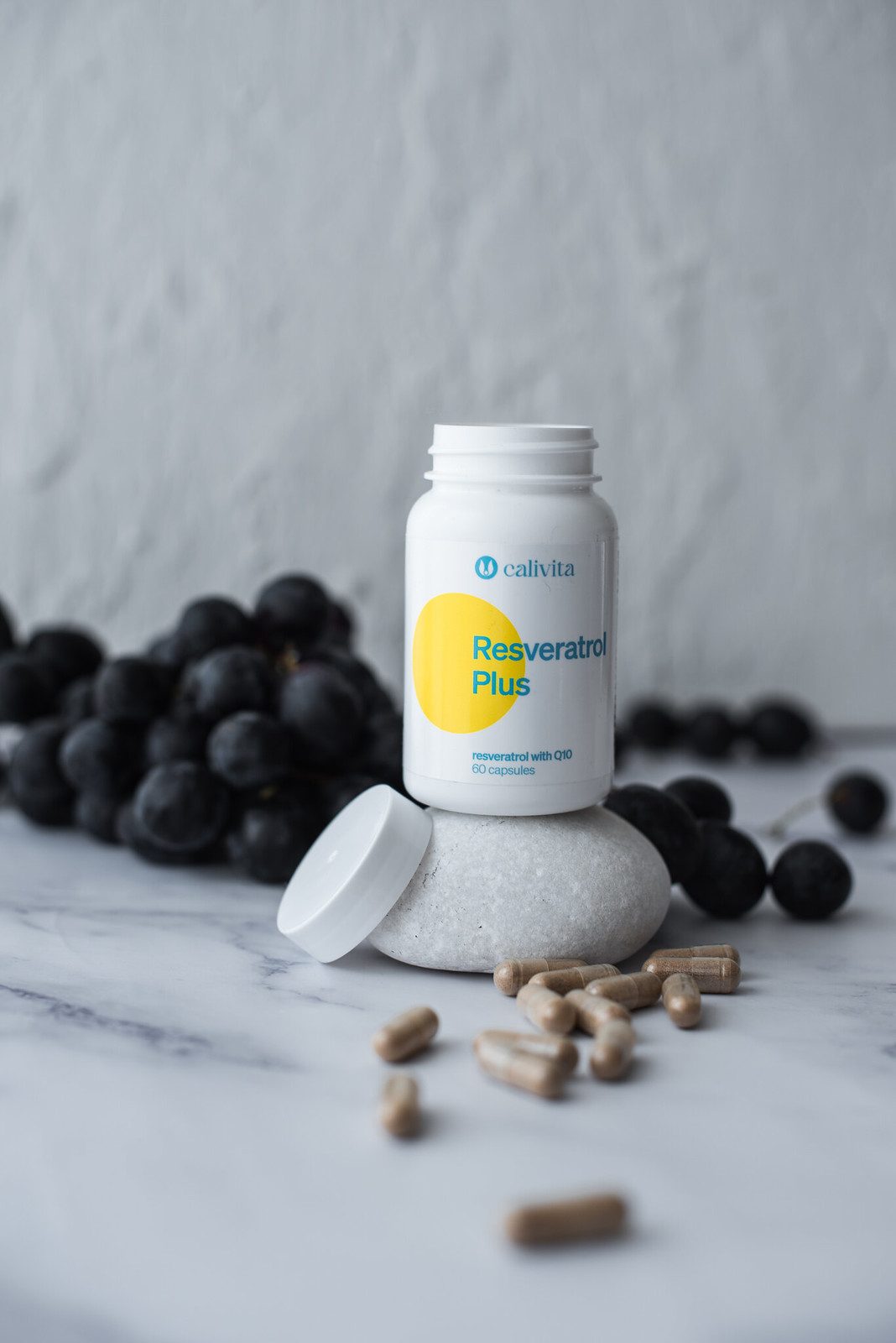 Flacon Resveratrol Plus desfacut, cu capsulele langa, si un ciorchinde de struguri negri